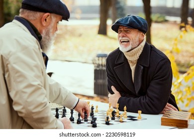 Portrait of two senior men playing chess in the park on a daytime in fall. Happy and delightful. Concept of leisure activity, friendship, sport, autumn season, game, entertainment, old generation - Shutterstock ID 2230598119