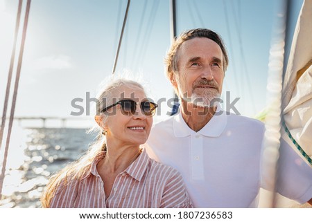 Portrait of two senior people looking away. Mature couple standing on yacht enjoying their sailing trip.