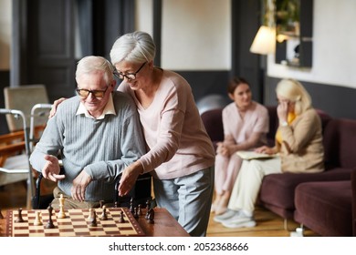Portrait of two senior people playing chess and enjoying activities in retirement home, copy space