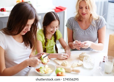 Portrait Of Two Sisters And Their Mother Cooking Pastry In The Kitchen