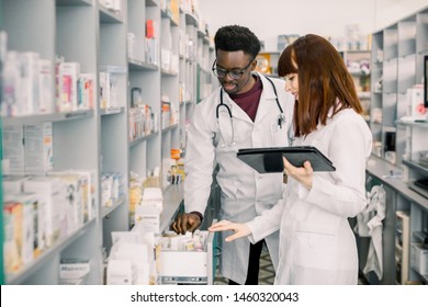 Portrait of two smiling friendly multiethnical pharmacists working in modern pharmacy and making order for medicines in distribution company - Shutterstock ID 1460320043