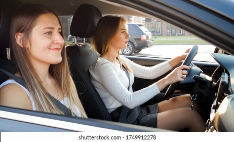 Porträt zweier lächelnder Mädchen, die bei Sonnenuntergang im Auto fahren.