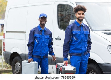 Portrait Of Two Smiling Manual Workers With Their Tool Boxes Standing Near The White Van