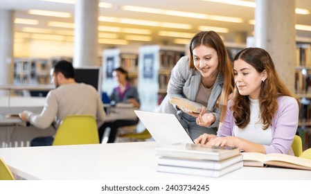 Portrait of two smiling woman working in university library - Powered by Shutterstock