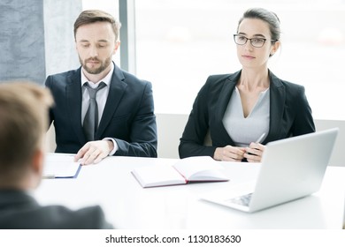 Portrait Of Two Successful Business People, Man And Woman,  Listening To Partner Sitting Across Meeting Table In Conference Room, Copy Space