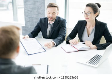 Portrait Of Two Successful Business People, Man And Woman,  Presenting Contract To Partner Sitting Across Meeting Table In Conference Room, Copy Space