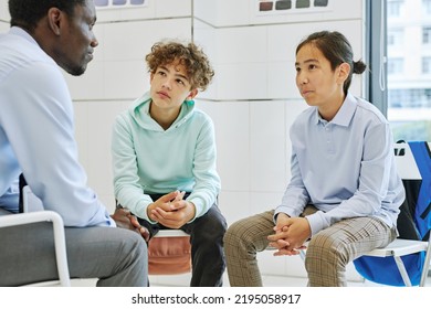 Portrait Of Two Teen Boys Listening To Counsellor In School Therapy Session