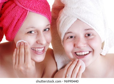 Portrait of two teenage girls are cleaning their faces with cotton pads
