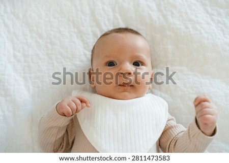Portrait of a two to three month old baby with visible drool on lips. Natural process of infant development associated with increased saliva production in early infancy.