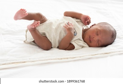 Portrait of two weeks African American newborn baby or infant lying on the white bed and open his eyes.