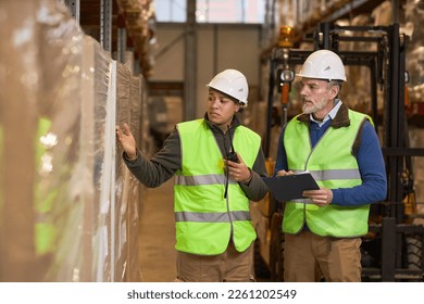 Portrait of two workers doing inspection at storage warehouse an wearing hardhats - Powered by Shutterstock