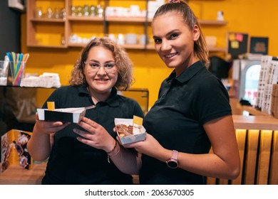 A portrait of two workers in a modern pastry shop showing the product they are selling. Selective focus. High quality photo - Shutterstock ID 2063670305