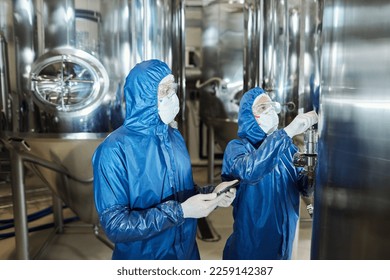 Portrait of two workers wearing protective gear while overseeing production process at factory workshop - Powered by Shutterstock