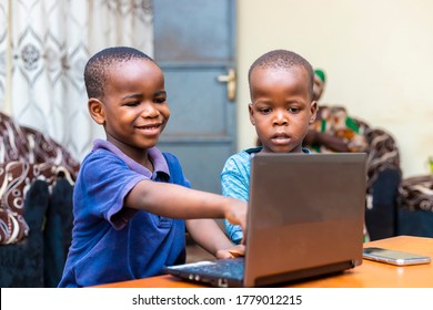 Portrait Of Two Young African Children At Home Playing Games Online With Laptop. Fascia Expression