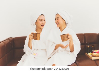 Portrait two young asian women relaxing in the living room drinking tea on the sofa after having clean shower preparing for spa together in their home : Happiness woman who loves beauty.