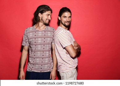 Portrait of a two young confident twin brothers isolated over red background, posing