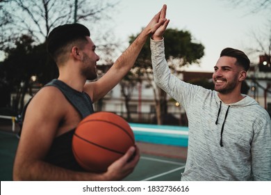 Portrait Of Two Young Friends Playing Basketball And Having Fun On Court Outdoors. Sport Concept.