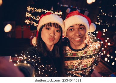 Portrait of two young people couple take selfie kiss lips celebrate xmas new year garland lights flat indoors - Powered by Shutterstock