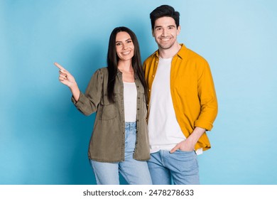 Portrait of two young people point finger empty space wear shirt isolated on blue color background - Powered by Shutterstock