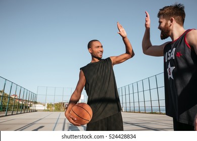 Portrait Of A Two Young Sports Men Giving High Five While Playing Basketball At The Playground