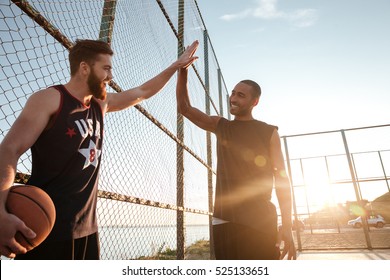 Portrait Of A Two Young Sports Men Giving High Five While Playing Basketball At The Playground