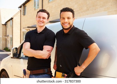 Portrait of two young tradesmen by their van