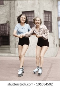 Portrait Of Two Young Women With Roller Blades Skating On The Road And Smiling