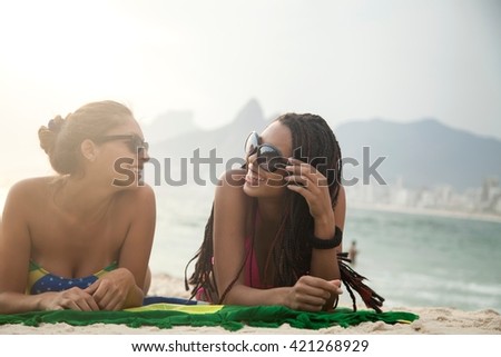 Portrait of two young women sunbathing on Brazilian flag, Ipanema beach, Rio De Janeiro, Brazil