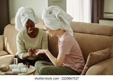 Portrait of two young women with towels doing manicure at home while enjoying self care day together - Powered by Shutterstock