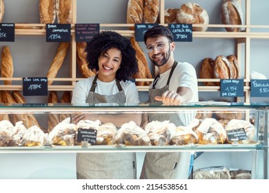 Portrait of two younger owners selling fresh pastry and loaves un bread section and smiling at pastry shop. - Powered by Shutterstock