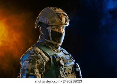 Portrait of a Ukrainian armed forces soldier in full equipment against yellow blue smoke on a dark background, concept of military conflict in Ukraine - Powered by Shutterstock