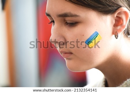 Portrait of Ukrainian girl with national flag on cheek, patriot of Ukraine teen girl. 