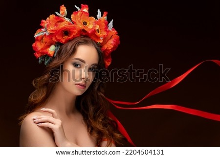 Portrait of a Ukrainian girl in a wreath of bright red poppies with fluttering ribbons. National traditional flower headdress. Ukraine concept. Stop the war. High quality photo
