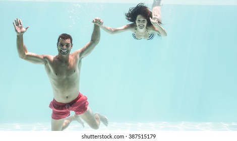 Portrait of underwater couple holding hands and enjoying in swimming pool - Powered by Shutterstock