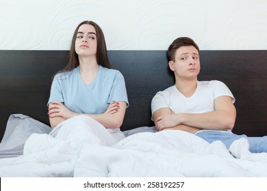 Portrait of unhappy and annoyed young caucasian couple after quarreling in bedroom under stress. Upset man and woman secretly watching each other because mistake, relationship and marriage sex problem