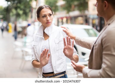 Portrait  of unhappy girl getting rid of unwelcome stranger outdoors - Shutterstock ID 1015476307