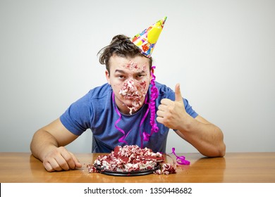 Portrait Unhappy Good-looking Birthday Guy With Cake On Face Showing Thumb Up, Unhappy With Surprise Party That Friends Made For Him. 