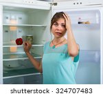 Portrait of unhappy and hungry girl near empty fridge