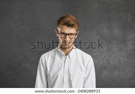 Portrait of unhappy millennial gen z man on black studio background look depressed frustrated with news. Mad angry young Caucasian male in glasses feel unsure doubtful. Doubt, boredom concept.