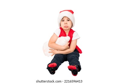 Portrait Of Unhappy Resentful Little Child In Red Santa Claus Hat Isolated On White Background. Beautiful Five-year European Boy. Bad Gift. Copy Space. Merry Christmas. Bad Mood. Close-up. New Year.