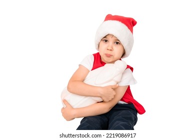 Portrait Of Unhappy Resentful Little Child In Red Santa Claus Hat Isolated On White Background. Beautiful Five-year European Boy. Bad Gift. Copy Space. Merry Christmas. Bad Mood. Close-up. New Year.