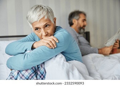 Portrait of unhappy senior woman or couple during or after arguing while sitting on bed, married elderly couple discussing in bed, or a health problem, mature woman being in pain - Powered by Shutterstock