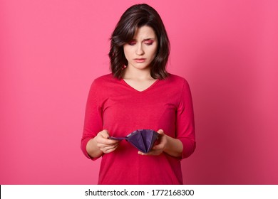 Portrait Of Unhappy Stressed Beautiful Lady Looking In Open Empty Wallet With Upset Expression. Young Woman Spent Too Much Money During Shopping, No Money Left For Life.