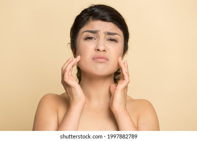 Portrait Of Unhappy Young Indian Woman Isolated On Yellow Studio Background Touch Face Worry About Pimples Wrinkles. Upset Mixed Race Female Think Of Treatment. Facial Skincare Concept.