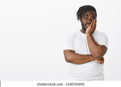 Portrait Of Unimpressed Shocked Young African Male In White T-shirt, Holding Palm On Face And Gazing With Contempt At Camera, Being Impressed With How Stupid Person Is Over White Background