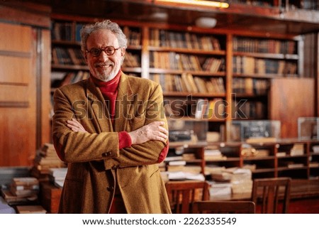 A portrait of university professor standing  in the campus library, smiling and looking at the camera with copy-space.