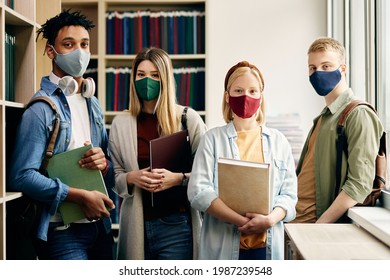 Portrait Of University Students With Face Masks Studying In Library And Looking At Camera.