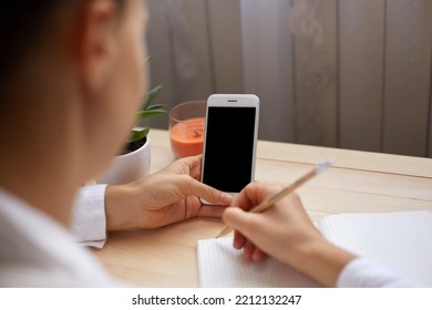 Portrait Of Unknown Anonymous Woman Posing Backwards And Holding Smart Phone With Empty Display For Advertisement, Writing Something In Paper Organizer.