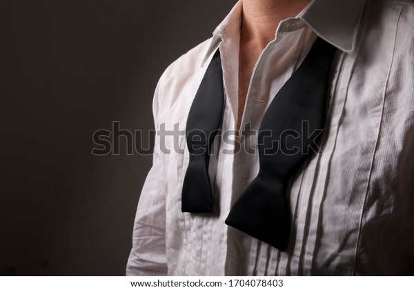 Portrait of\
unrecognizable man with bow tie hanging loose around the collar of\
a unbuttoned disheveled white tuxedo\
shirt