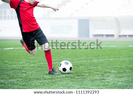 Portrait of unrecognizable teenage boy kicking ball playing football on stadium during practice, copy space